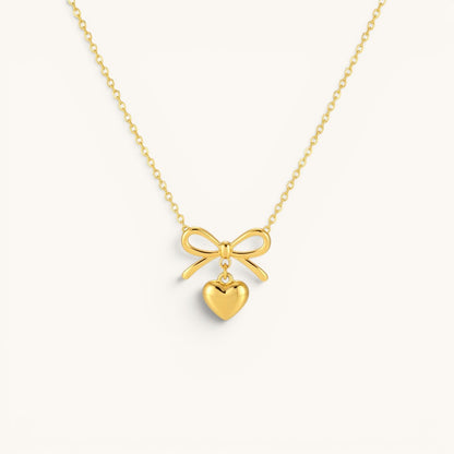 TITLIYA gold-tone necklace featuring a delicate bow pendant with a dangling heart charm for elegant daily wear.