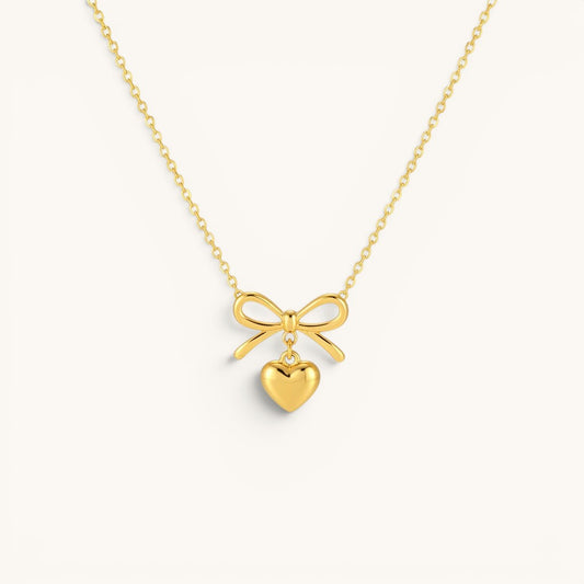 TITLIYA gold-tone necklace featuring a delicate bow pendant with a dangling heart charm for elegant daily wear.