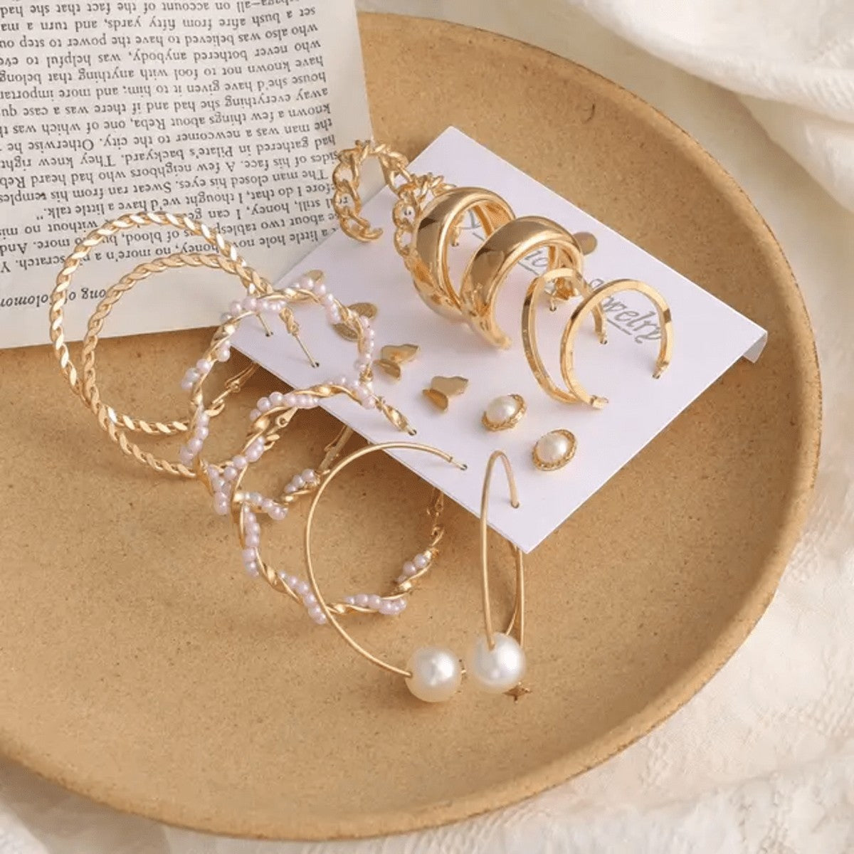 TITLIYA set of 9 golden Korean earrings featuring hoops, pearl accents, and butterfly studs on a decorative plate.