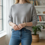 Woman wearing a TITLIYA gold-tone tulip bracelet with green stones, styled with a grey sweater and blue jeans.