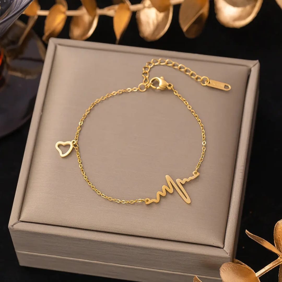 TITLIYA gold-tone heartbeat and heart charm bracelet and anklet with an adjustable chain on a display box.
