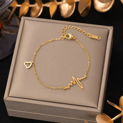 TITLIYA gold-tone heartbeat and heart charm bracelet and anklet with an adjustable chain on a display box.