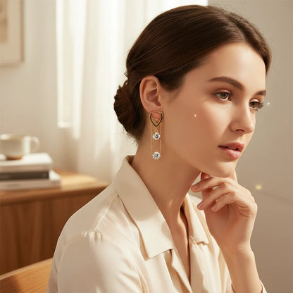 Woman wearing elegant TITLIYA gold-tone hanging earrings with two sparkling diamond-like stones in a bright room.