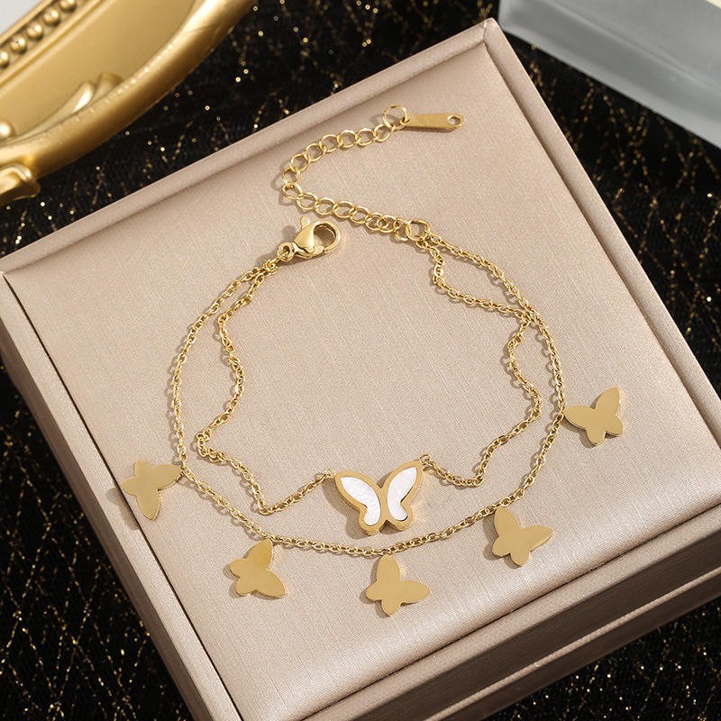 TITLIYA gold-toned layered chain bracelet featuring white butterfly charms and an adjustable lobster clasp closure.