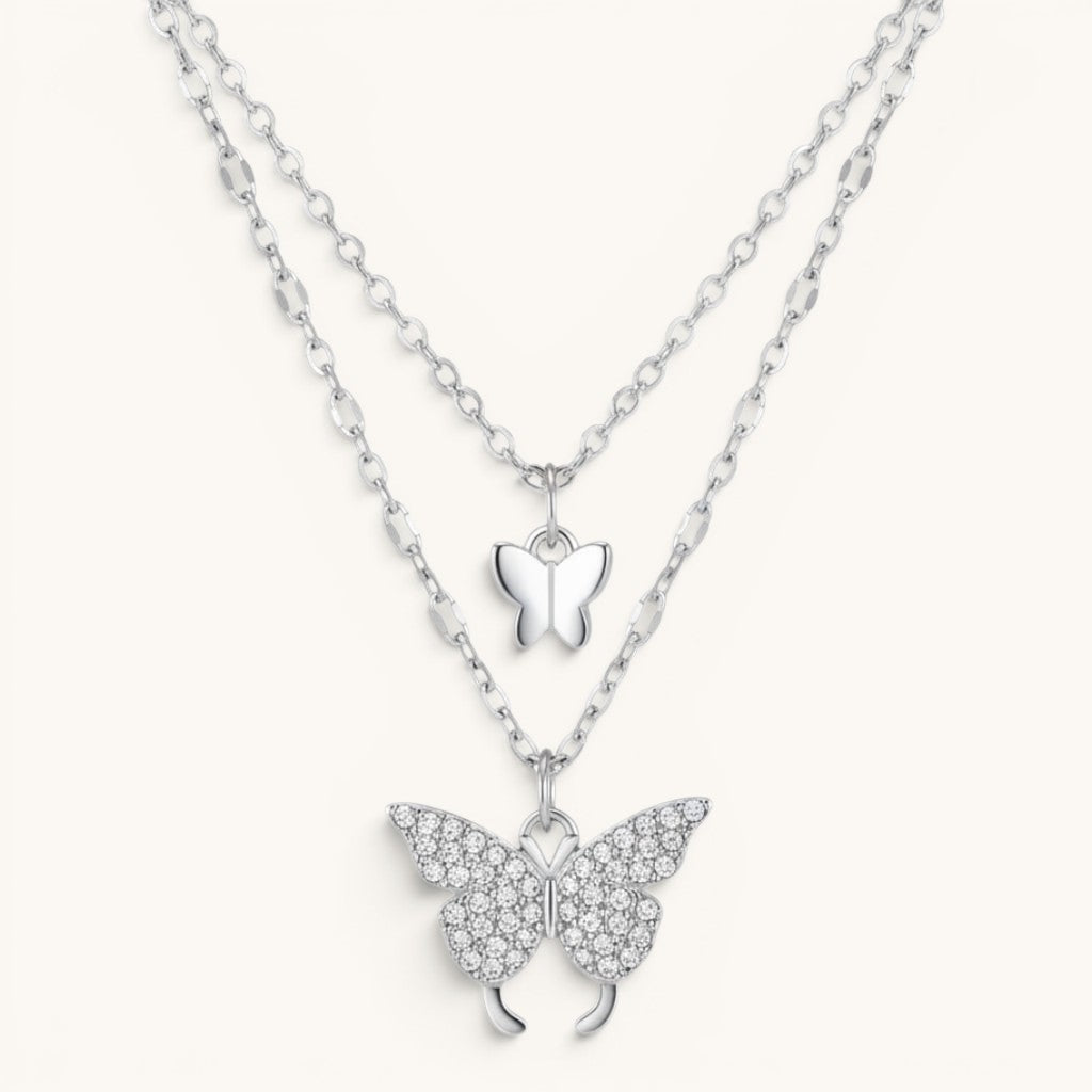 TITLIYA silver-tone layered necklace featuring a small smooth butterfly charm and a crystal-encrusted butterfly pendant.