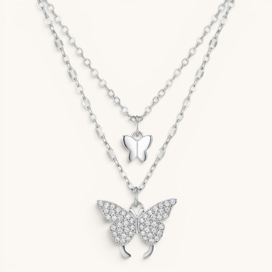 TITLIYA silver-tone layered necklace featuring a small smooth butterfly charm and a crystal-encrusted butterfly pendant.