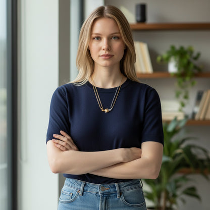 Woman wearing a TITLIYA gold and silver magnet handshake couple necklace with a navy blue top in a bright room.