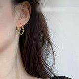 TITLIYA medium gold twisted hoop earring worn on a woman's ear for an elegant daily look.