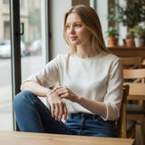 Woman wearing a TITLIYA multicolour tulip bracelet with a white top and jeans, sitting in a cafe.