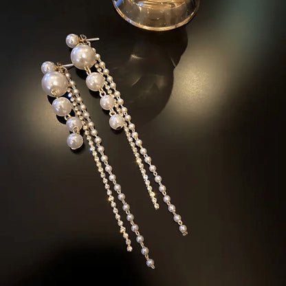 TITLIYA elegant Korean-style long drop earrings featuring white pearls and delicate crystal chains on a black surface.