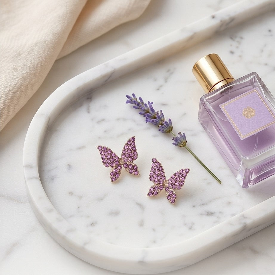 TITLIYA pink butterfly stud earrings with crystal embellishments on a marble tray with lavender and perfume.