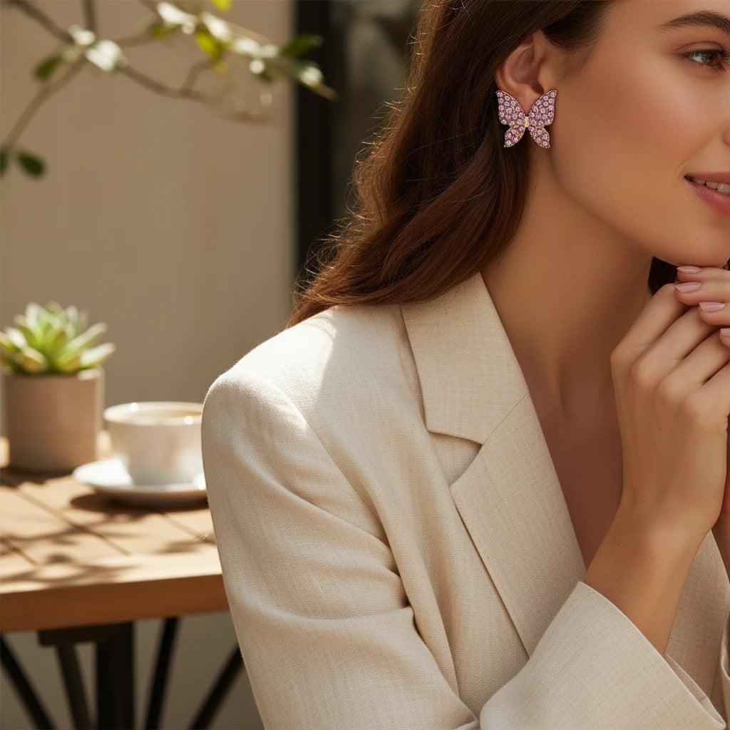 TITLIYA pink butterfly stud earrings worn by a woman in a beige blazer, featuring delicate crystal detailing.