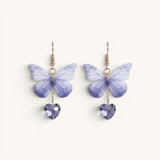 TITLIYA purple butterfly earrings with soft gradient wings and heart-shaped crystal drops on gold-tone hooks.