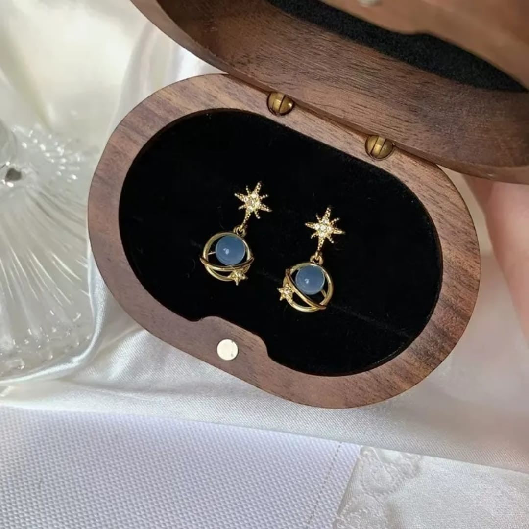 TITLIYA gold-tone Saturn design earrings with blue spherical beads and star accents in a wooden jewelry box.
