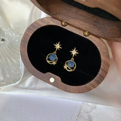 TITLIYA gold-tone Saturn design earrings with blue spherical beads and star accents in a wooden jewelry box.