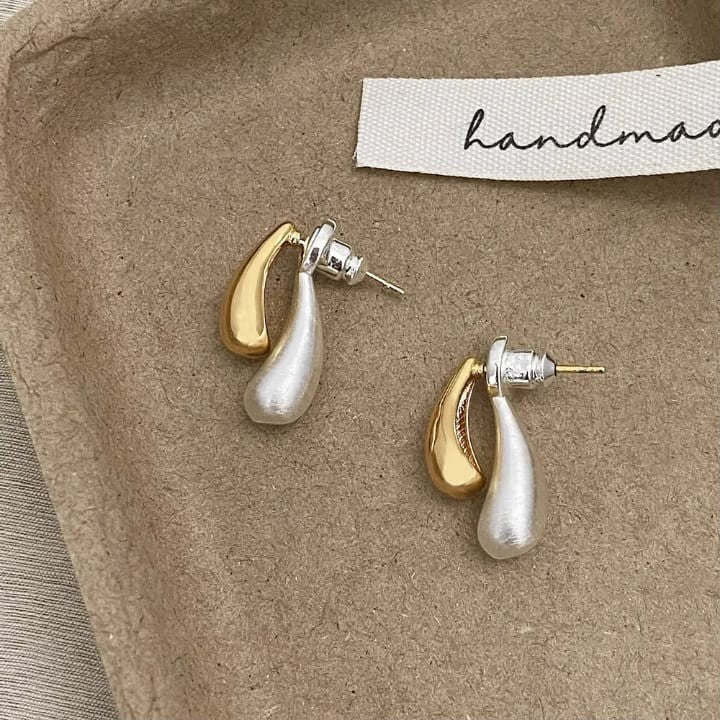 TITLIYA silver and gold double drop earrings with a modern teardrop design on a textured handmade display tray.