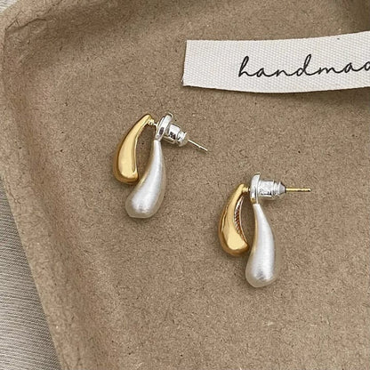 TITLIYA silver and gold double drop earrings with a modern teardrop design on a textured handmade display tray.