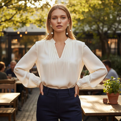 Woman wearing TITLIYA gold star drop earrings with dangling pearls, styled with a white blouse in an outdoor cafe.