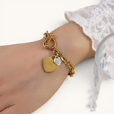 TITLIYA gold-tone chain bracelet featuring a polished heart and a crystal-encrusted heart charm with a toggle clasp.