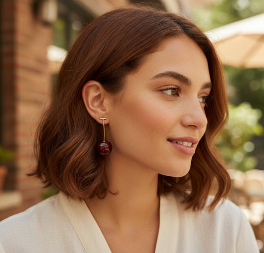 Woman wearing TITLIYA Western cherry drop earrings with a glossy red fruit charm on a gold-tone stem.