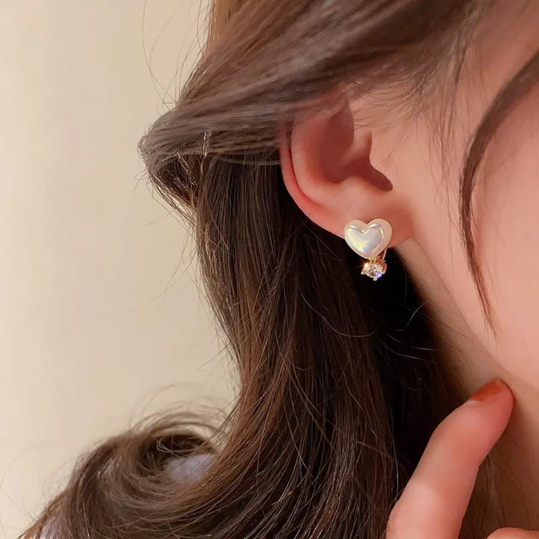 TITLIYA white heart-shaped stud earring with a small sparkling diamond accent worn on a woman's ear