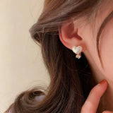 TITLIYA white heart-shaped stud earring with a small sparkling diamond accent worn on a woman's ear