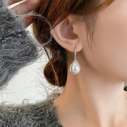 TITLIYA elegant white teardrop pearl earring with gold-tone hook, worn by a woman in a grey sweater.